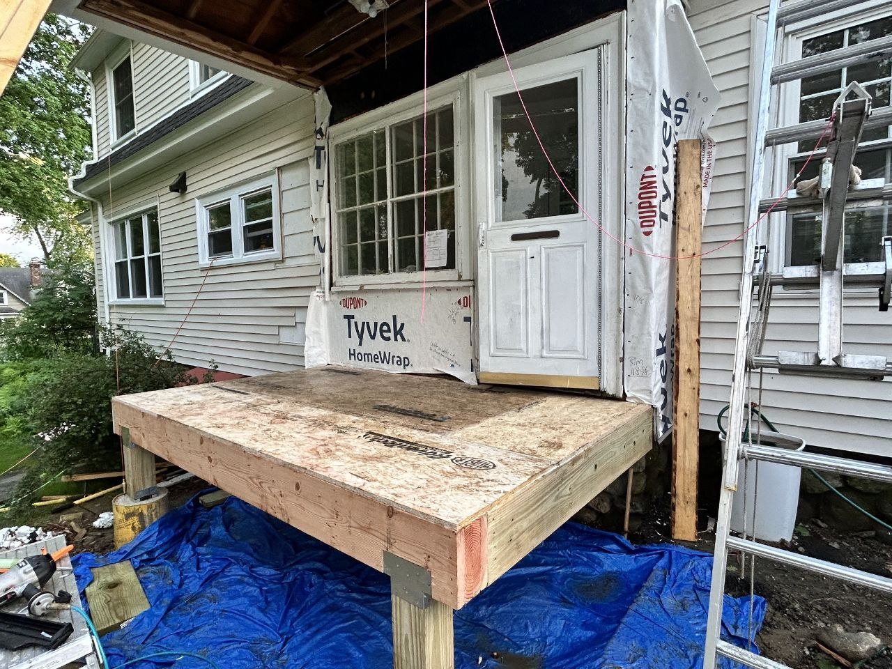 Before: the same addition mid-build, subfloor framed and the wall wrapped in house wrap